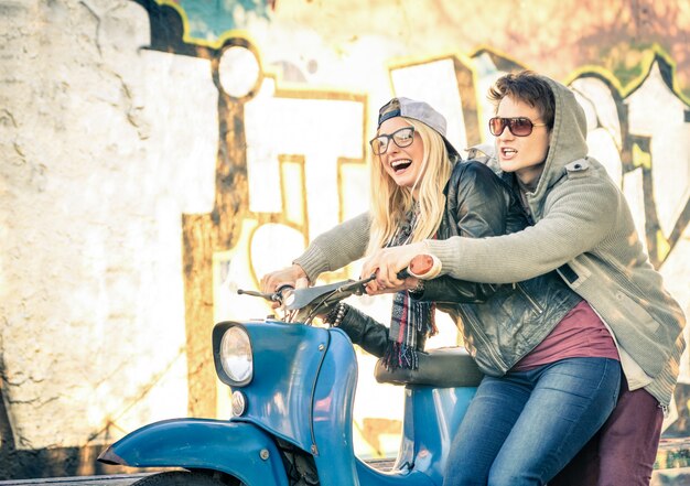 Foto jovem casal de amantes se divertindo em uma moto scooter vintage