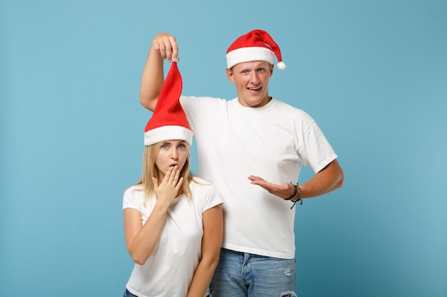 Jovem casal de amigos do papai noel confuso, cara e mulher com chapéu de natal posando