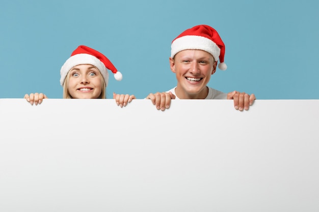 Jovem casal de amigos do Papai Noel sorridente, cara e mulher com chapéu de Natal