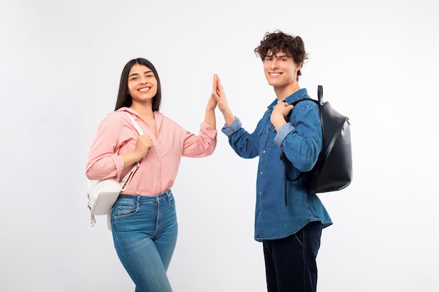 Jovem casal de estudantes alegres compartilhando um fundo branco de cinco altos