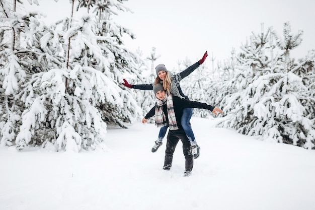 Jovem casal de férias de inverno em um bosque nevado feliz e sorrindo sinceramente