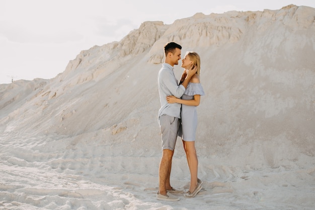 Jovem casal de homem e mulher abraçando ao ar livre no deserto.