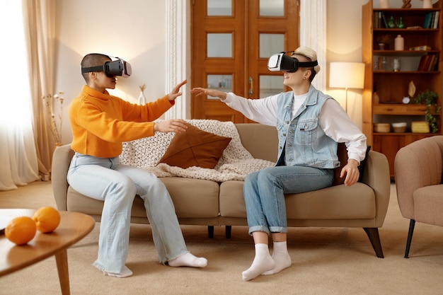 Foto jovem casal de lésbicas usando óculos vr jogando videogame com experiência realidade virtual em casa conceito de amizade lgbt e passatempo feliz juntos