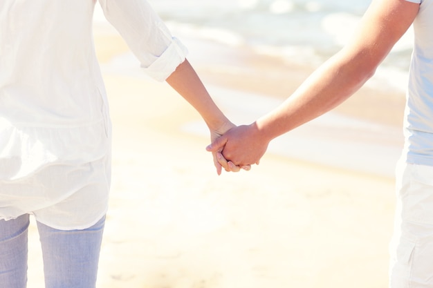 Jovem casal de mãos dadas na praia