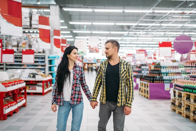 Jovem casal de mãos dadas no supermercado, vista traseira