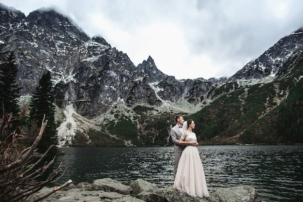 Jovem casal de noivos posando na margem do lago morskie oko, polônia, tatra