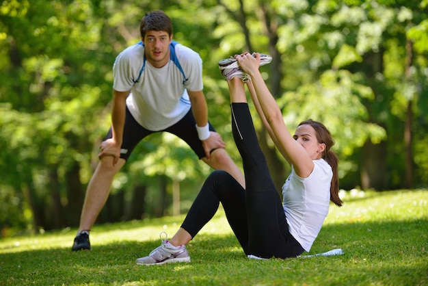 Foto jovem casal de saúde fazendo exercícios de alongamento relaxando e aquecendo depois de correr e correr no parque