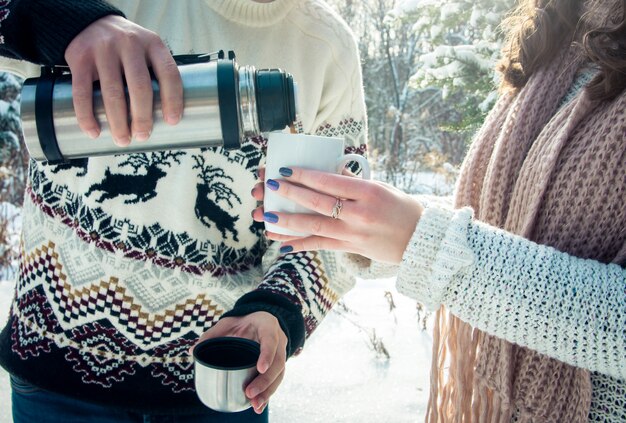 Jovem casal derrama chá quente de garrafa térmica na floresta