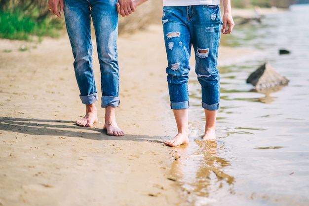 Jovem casal descalço andando na praia. pés no verão de água