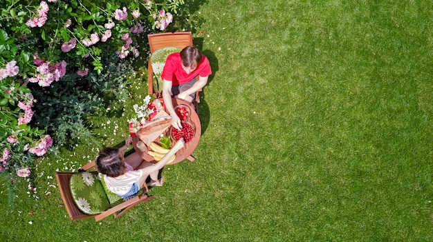 Jovem casal desfrutando de comidas e bebidas em um lindo jardim de rosas em um encontro aéreo romântico