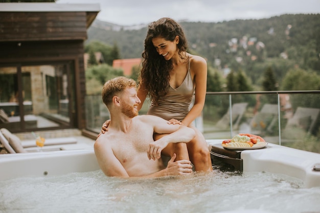 Jovem casal desfrutando na banheira de hidromassagem ao ar livre de férias