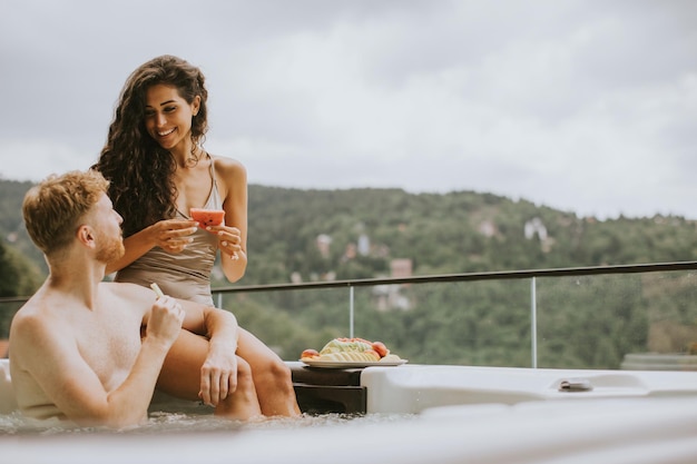 Jovem casal desfrutando na banheira de hidromassagem ao ar livre de férias