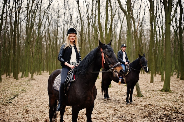 Jovem casal elegante, andar a cavalo na floresta de outono