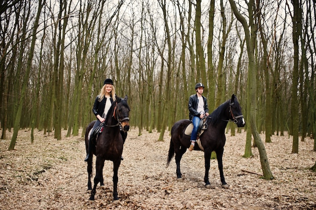 Jovem casal elegante, andar a cavalo na floresta de outono