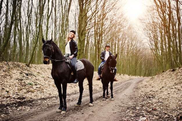 Jovem casal elegante, andar a cavalo na floresta de outono