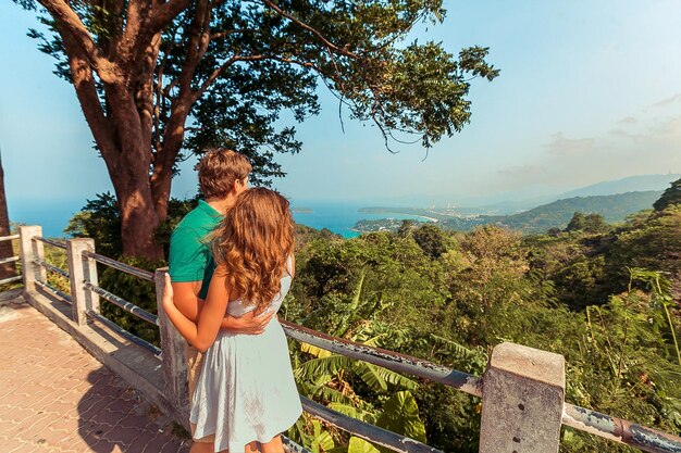 Jovem casal em pé na ponte e olhando para o mar. phuket. tailândia. vista traseira. bela paisagem tropical