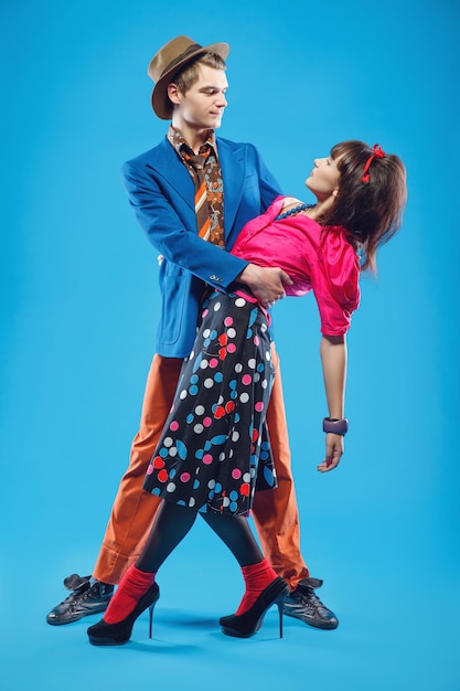 Jovem casal em roupas coloridas à moda antiga no estilo pinup dançando