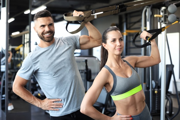 Jovem casal em treinamento corporal com trx no ginásio.