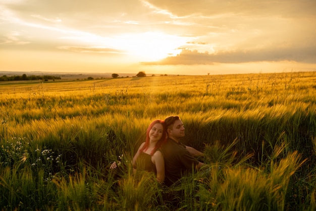 Jovem casal em um campo de trigo ao pôr do sol