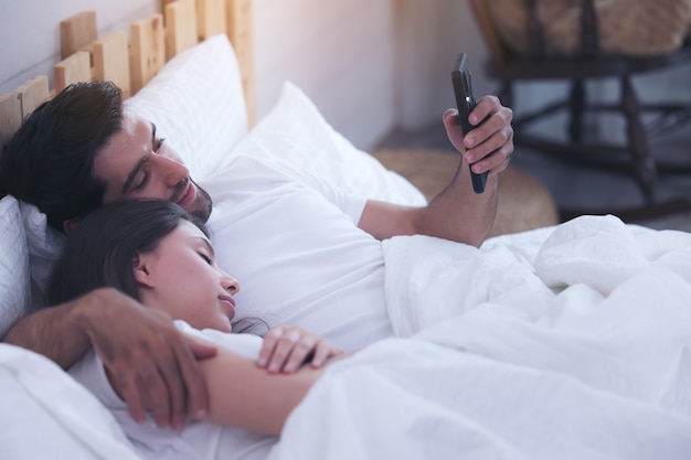 Jovem casal em uma cama com telefones celulares