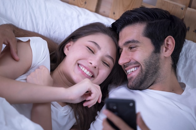 Jovem casal em uma cama com telefones celulares