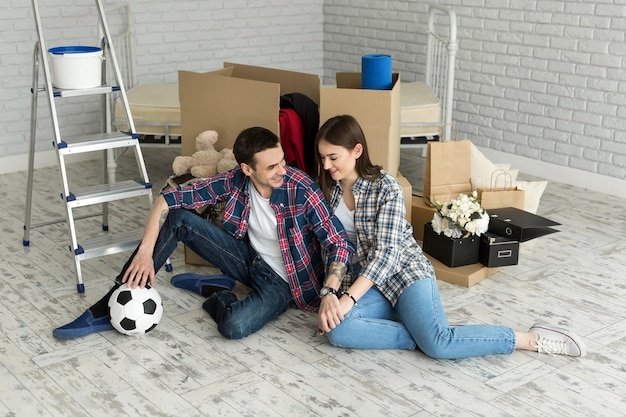 Jovem casal em uma nova casa relaxante no fundo de grandes caixas