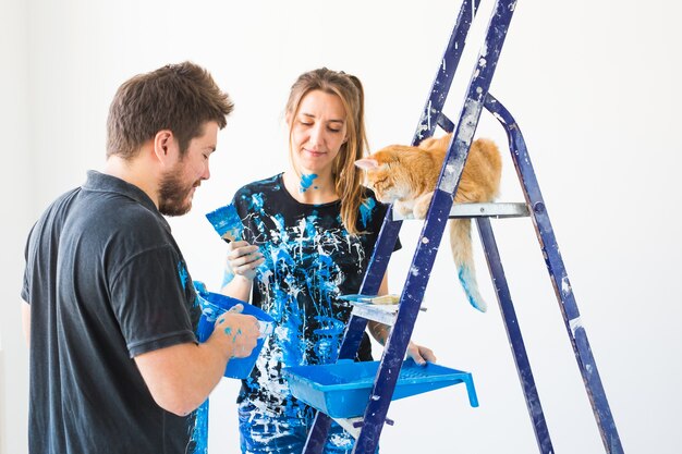 Jovem casal engraçado com gato fazendo renovação no apartamento novo.