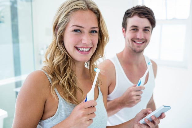 Jovem casal escovando os dentes em casa no banheiro