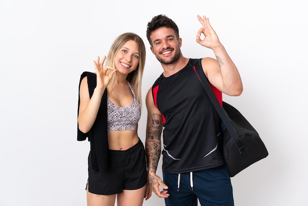 Jovem casal esporte em branco mostrando um sinal de ok com os dedos