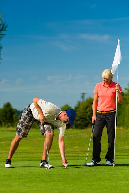 Jovem casal esportiva jogando golfe em um curso