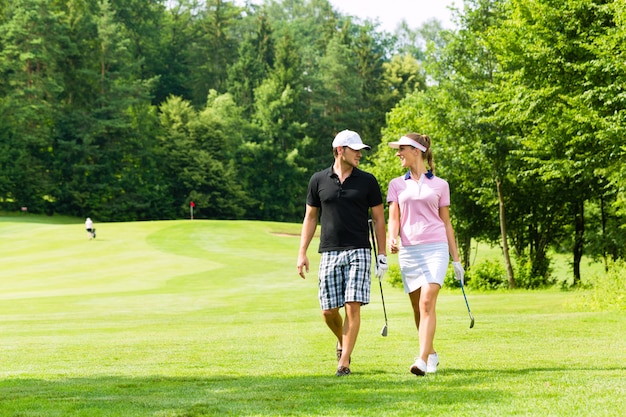 Jovem casal esportiva jogando golfe em um curso