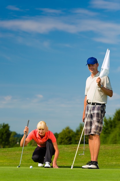 Jovem casal esportiva jogando golfe em um curso