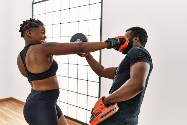 Jovem casal esportivo afro-americano boxe no centro esportivo.