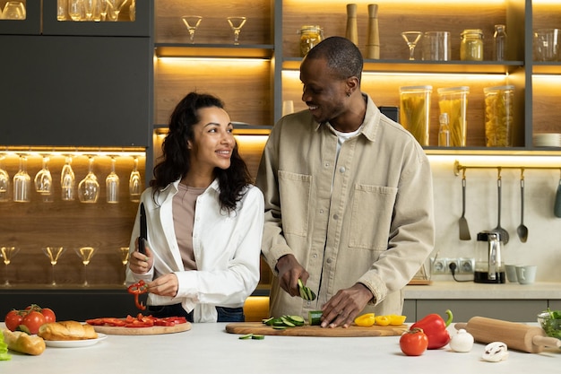 Jovem casal fala cortando legumes frescos para salada