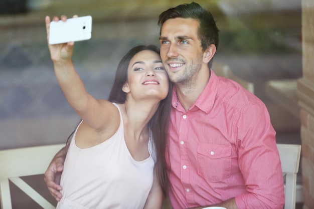 Foto jovem casal faz selfie no café