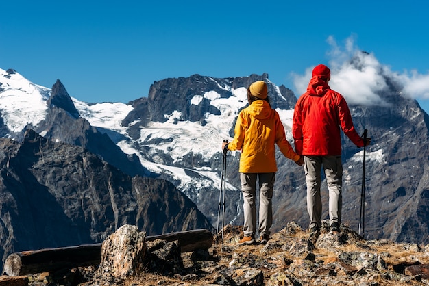 Jovem casal fazendo caminhada nórdica nas montanhas, vista traseira. um casal ativo está envolvido em caminhadas. um jovem casal está empenhado em rastreamento. trekking e caminhada nórdica. caminhada. copie o espaço