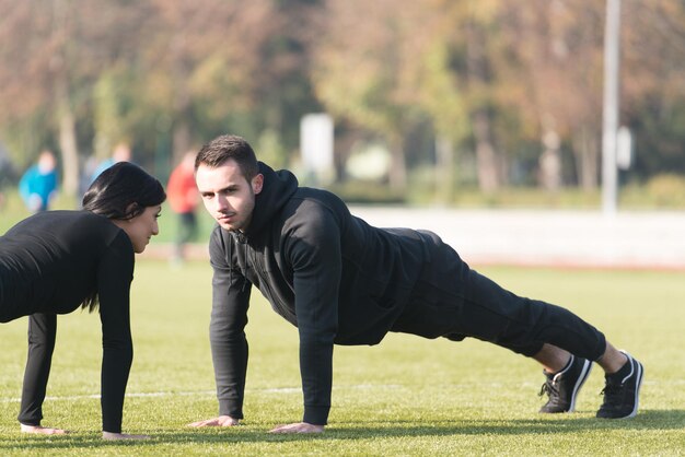 Jovem casal fazendo flexões na área do parque da cidade, treinando e exercitando para o conceito de estilo de vida saudável de fitness de resistência ao ar livre