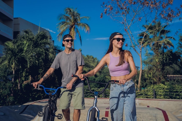 Jovem casal feliz a desfrutar de um passeio de BMX no skatepark