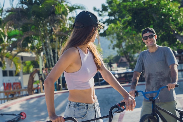 Jovem casal feliz a desfrutar de um passeio de BMX no skatepark