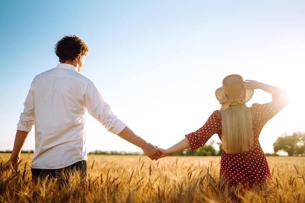 Jovem casal feliz abraçando em um campo de trigo no pôr do sol aproveitando o tempo juntos