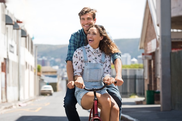 Jovem casal feliz andando de bicicleta juntos