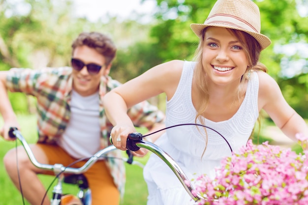 Jovem casal feliz andando de bicicleta pelo parque