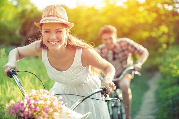 Jovem casal feliz andando de bicicleta pelo parque