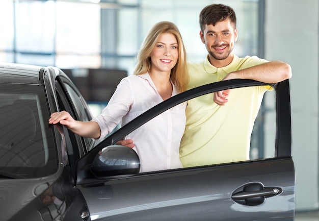 Jovem casal feliz andando de carro sorrindo - conceito de comprar carro