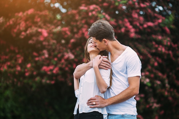 Jovem casal feliz apaixonado ao ar livre. amar o homem e a mulher em uma caminhada em um parque florido de primavera