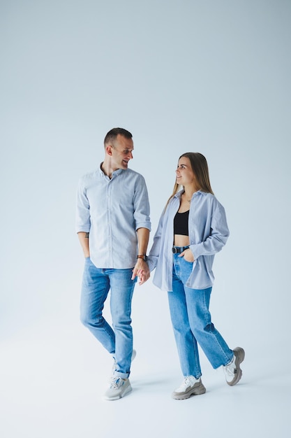 Jovem casal feliz apaixonado em jeans e camisas em um fundo branco Homem e mulher românticos sorridentes