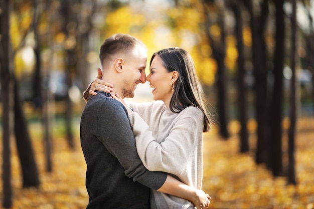 Foto jovem casal feliz apaixonado em um encontro rindo e se abraçando no parque outono