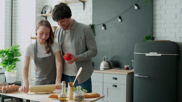 Jovem casal feliz aproveitando e preparando uma refeição saudável na cozinha