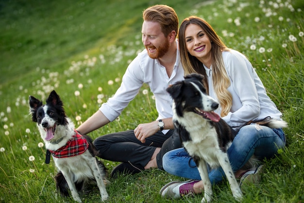 Foto jovem casal feliz brincando com cachorros, se divertindo no parque ao ar livre