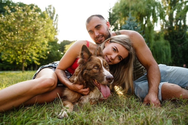 Jovem casal feliz brincando com seu cachorro sorrindo no parque